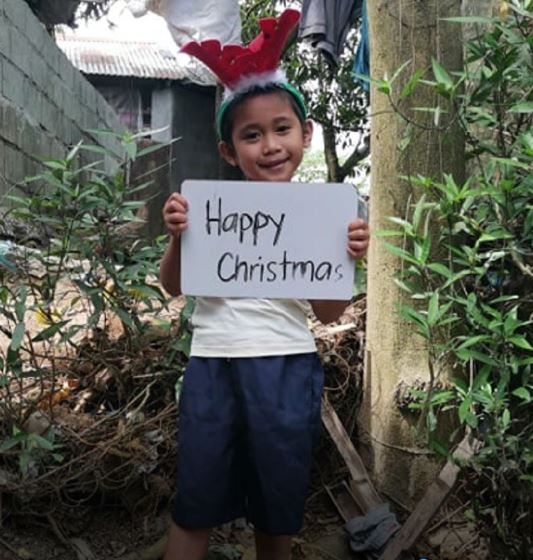 Child with merry Christmas banner